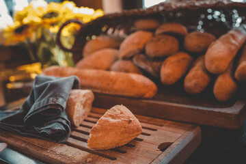 Fresh baguettes and bread rolls on wooden cutting board with knife and napkin. Rustic breakfast or...