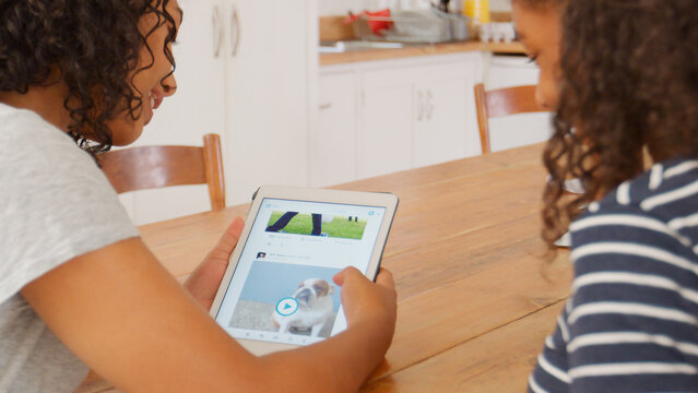 Close Up Of Two Teenage Girls Looking At Digital Tablet Together - Powered by Adobe