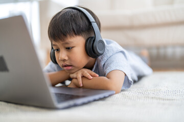 Asian boy using laptop with headphones course online learning, distance education for kids,...