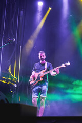 Bass guitarist playing on stage under colorful concert lights