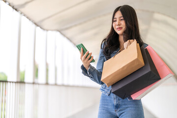 Woman holding smartphone browsing summer sale searching for deals at fashion store, shopping...