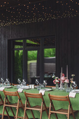 Elegant outdoor wedding reception venue with wooden chairs and green table decorations in a tranquil setting