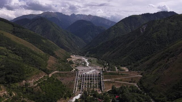A protective dam against mudflows. Talgar gorge, Tian Shan Mountains. Different vegetation and a mountain river. The view from the drone.