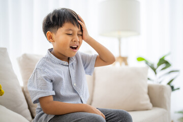 Portrait of sick depressed unhappy child boy touching on head feel suffering head ache pain flu...