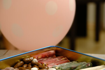 Eid candies. Traditional Turkish delights, almond candy and cocoa dragees in a blue metal gift box. Eid al-Fitr, Eid al-Adha. Close-up of a woman's hand taking almond candy from a box.