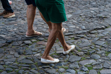 Half-length unidentified people walking on a cobblestone street during daytime.
