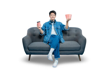 PNG,A cheerful young man on a sofa presents a combo of popcorn and a drink, ready for home...