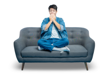 PNG,An amused young man covers his mouth to hold back a giggle while watching a funny movie on the sofa.
