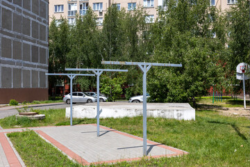 Outdoor metal drying racks installed on paved area in residential courtyard with apartment...