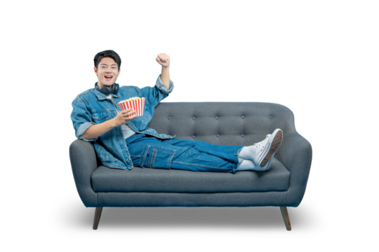 A smiling young man in a denim jacket relaxes on a sofa with a bucket of popcorn, enjoying a day of leisure at home.
PNG