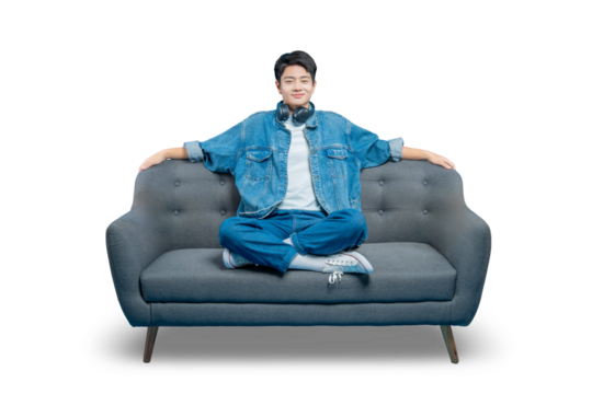 A happy young man in a denim jacket relaxes on a sofa with his arms resting on the back. Isolated on PNG background