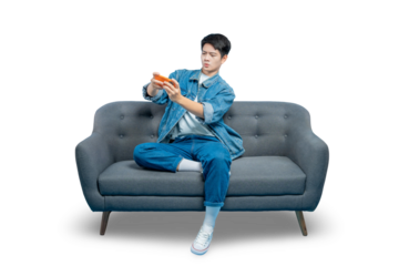 A young gamer sits on a sofa, looking focused and intense while playing a competitive game on his smartphone.PNG