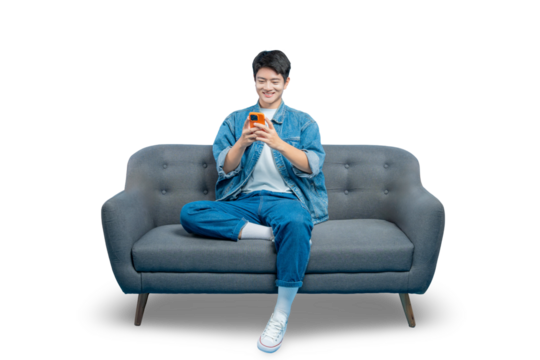 A smiling young man uses his smartphone for texting or social media while relaxing at home on the sofa.PNG