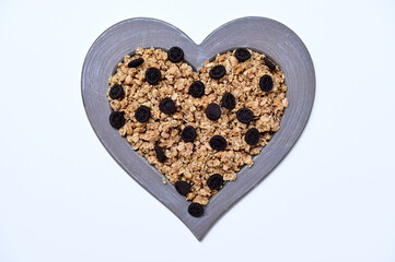 granola with chocolate cookies in a heart shaped frame on a white background