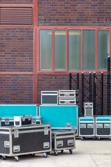 Group of black and blue flight cases in front of an old factory building