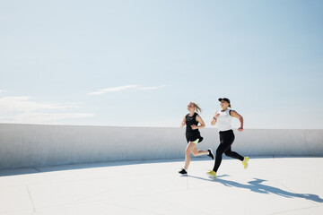 Two friends enjoying a spirited morning run on a sunlit rooftop, embracing fitness and fresh air in...