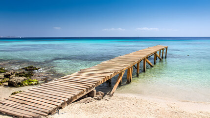 Fototapeta premium Wooden dock stretching into turquoise waters, serene beach backdrop. Tranquil escape into nature's beauty.