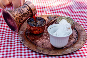 Traditional Turkish coffee brewed in cezve on sand, served in small mug of sweet