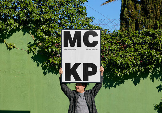 Mockup Of Man Holding Vertical Customized Framed Print Above Head