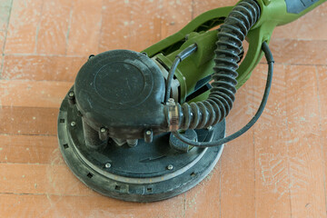 Olive Green Electric Random Orbital Sander with Black Cord on Wooden Floor, DIY Home Renovation...