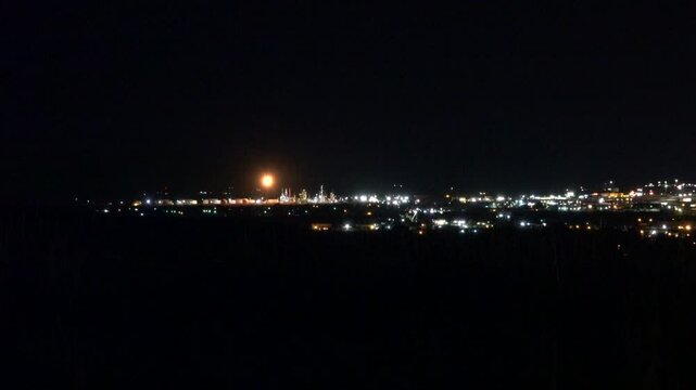 City lights of Casper, Wyoming at night with methane flare from petroleum refinery in distance.