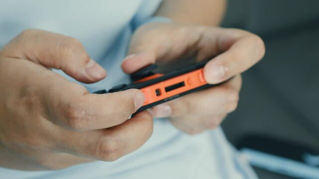 Close up view of hands gripping a portable video game console, highlighting the buttons and joystick in use as the player engages in intense gameplay, showcasing skill and concentration