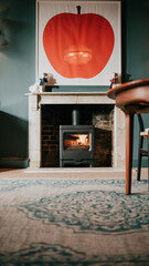A fireplace with a red apple painting on the wall
