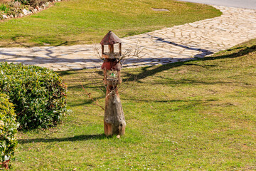 Rustic wooden birdhouse on a sunny lawn with stone path