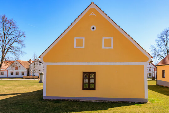 Traditional yellow house with white trim in sunny rural village landscape