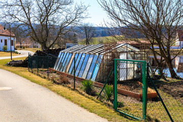 Rural greenhouse in countryside with bare trees and fenced pathway
