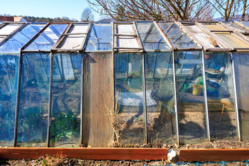 Rustic greenhouse with glass panels in rural setting on a sunny day
