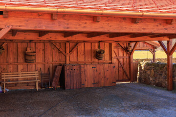 Rustic wooden carport and storage shed with red roof and brick flooring