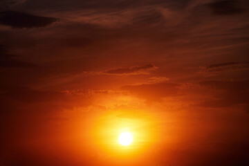 Beautiful colorful dramatic sky with clouds at sunset. Bright orange setting sun low on the horizon. Cirrus clouds change color from blue to yellow to red. Stunning backdrop, gorgeous scenery.