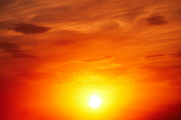 Beautiful colorful dramatic sky with clouds at sunset. Bright orange setting sun low on the horizon. Cirrus clouds change color from blue to yellow to red. Stunning backdrop, gorgeous scenery.