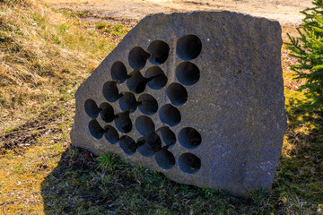 Abstract stone sculpture with circular holes in outdoor setting