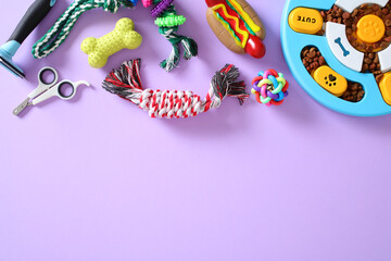 Assorted pet toys and grooming accessories on purple backdrop. Includes chew toys, rope, scissors,...