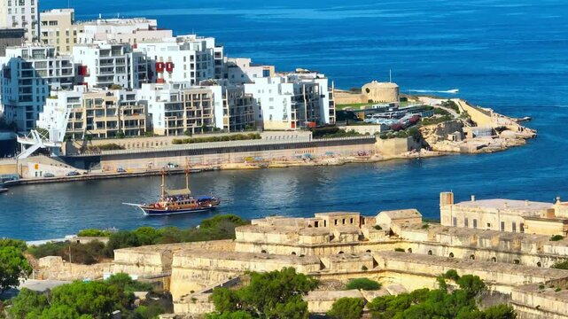 Manoel fort, tourist ship on Mediterranean sea, Sliema city on background. Maltese island
