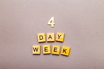 inscription four day week making by wooden cubes on grey background