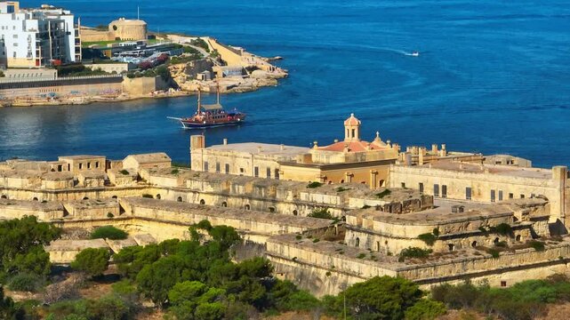 Manoel fort, tourist ship on Mediterranean sea, Sliema city on background. Malta island