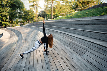 Woman Practicing Yoga and stretching on Amphitheater wooden Steps