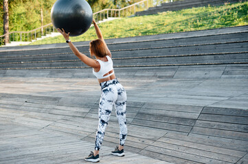 Woman Lifting Exercise Ball Outdoors