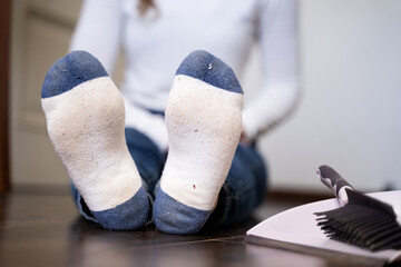 Front view close-up of dirty socks on woman’s feet after household cleaning, sitting in living...
