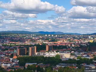 Naklejka premium Breathtaking panoramic view of a coastal city from a high mountain viewpoint. City buildings stretch toward the sea under a vast blue sky. Soft morning or sunset light, calm sea horizon