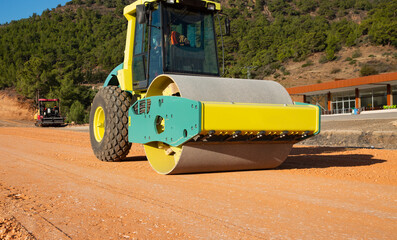 Road roller at work in Countryside - Workers repairs road under the program of planned 