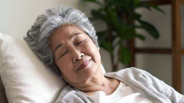 Happy elderly asian woman resting peacefully smiling with eyes closed indoors
