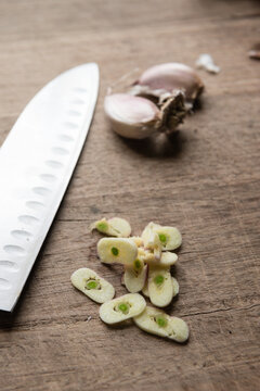 sliced garlic on a wooden board, with knife