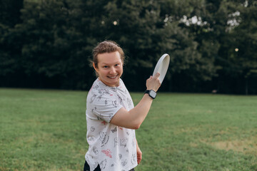 Smiling male looks directly wearing smartwatch and ponytail with frisbee lifted by shoulder in...