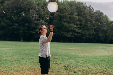 Focused male athlete standing mid-action under cloudy sky green field framed by trees hand raised...
