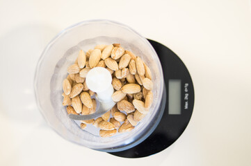 Overhead shot of almonds inside a grinder and on a scale for making cookies