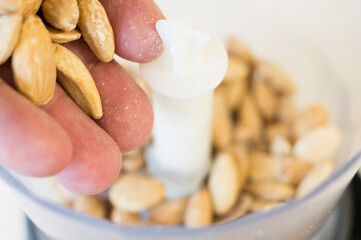 Person pouring almonds into the grinder to grind them